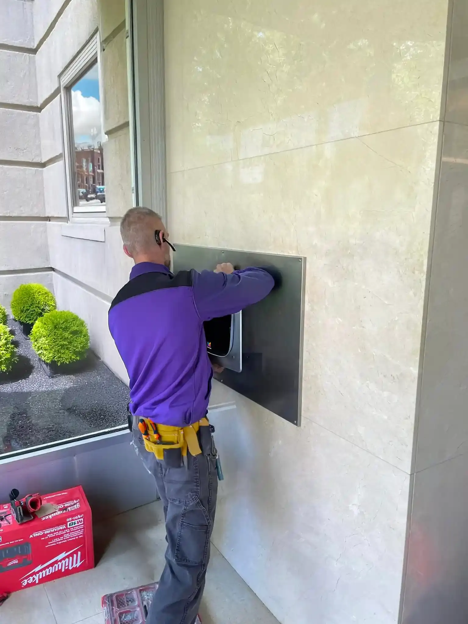 An installer setting a recessed ButterflyMX intercom into a stone wall