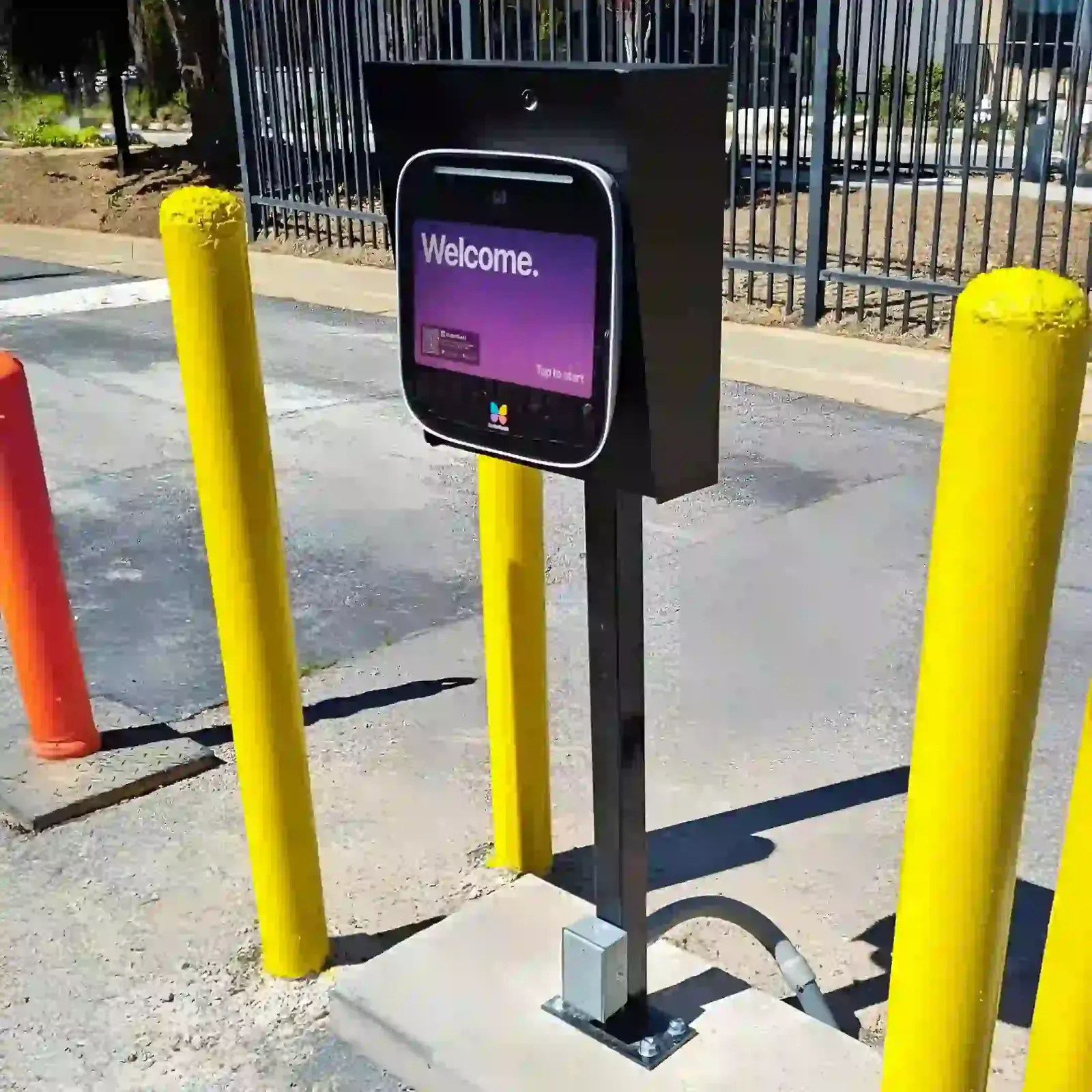 ButterflyMX 12-inch intercom on a pedestal at a driveway gate