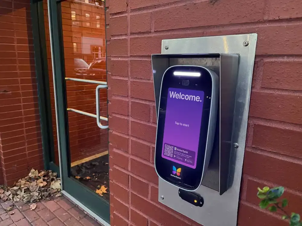 ButterflyMX intercom with a rain hood on a brick entry